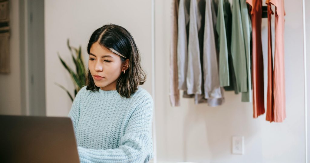 แม่ค้าออนไลน์กำลังบริหารร้านเสื้อผ้าแบบ Dropship ผ่านโน้ตบุ๊กภายในบ้าน